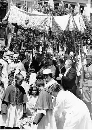 Fragment procesji na ul. Krakowskie Przedmieście. Widoczni m.in.: ks. arcybiskup Filippo Cortesi (niesie monstrancję), minister wyznań religijnych i oświecenia publicznego Wojciech Świętosławski (w okularach, podtrzymuje rękę celebransa), prezes Najwyższej Izby Kontroli Państwa Jakub Krzemieński (podtrzymuje drugą rękę celebransa).