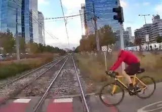 Rowerzysta wjeżdża pod tramwaj na czerwonym świetle. Nagranie 