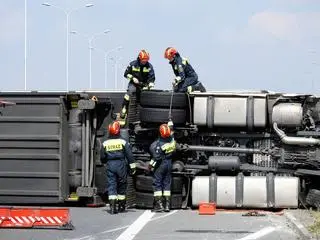 Przy podniesieniu ciężarówki pracuje grupa techniczna straży pożarnej