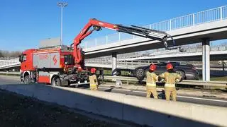 Strażacy usuwają auto, które zawisło na barierach przy zjeździe z S8