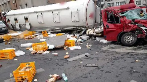 Skrzyżowanie zasypane pieczywem i paszą. Ciężarówka na boku, pod nią samochód dostawczy