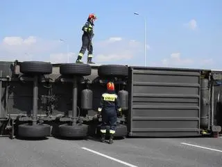 Przy podniesieniu ciężarówki pracuje grupa techniczna straży pożarnej