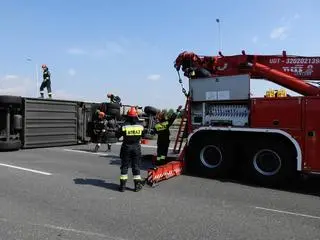 Przy podniesieniu ciężarówki pracuje grupa techniczna straży pożarnej