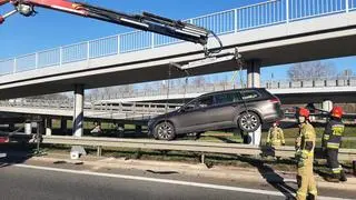 Strażacy usuwają auto, które zawisło na barierach przy zjeździe z S8