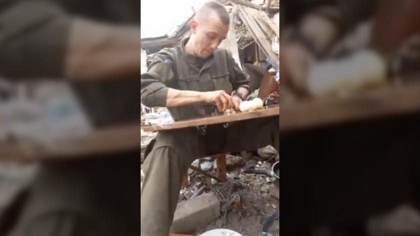 Ukraiński żołnierz kroi cebulę pod ostrzałem