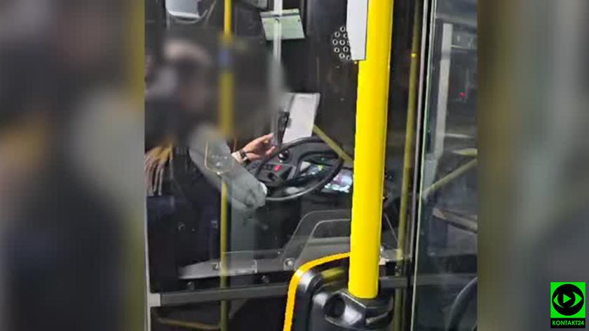 Kierowca prowadzi autobus z telefonem w ręce