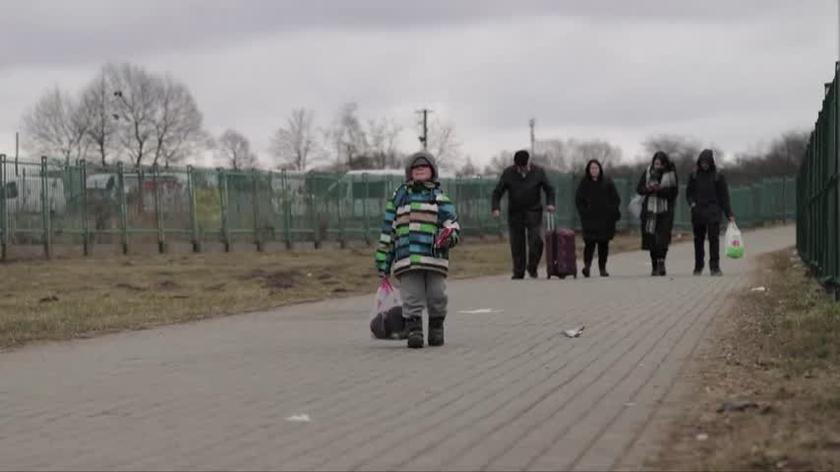 Mały chłopiec kroczy za mamą w stronę przejścia granicznego w Medyce