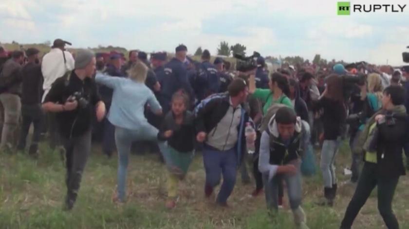 Imigranci uciekają przed policją. Operatorka kamery kopie i podstawia im nogę