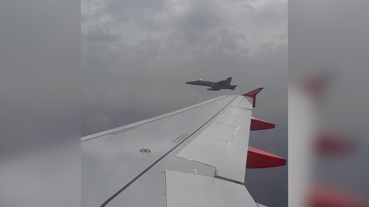 Un avión de Easyjet escoltado por un caza español F-18.  registro