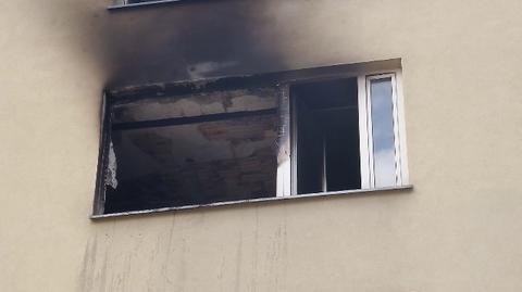 Strażacy wyrzucają z mieszkania spalone rzeczy