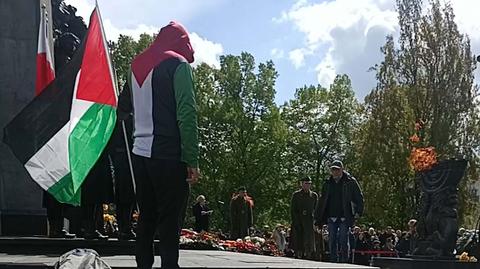 Mężczyzna stanął przy pomniku z flagą Palestyny 